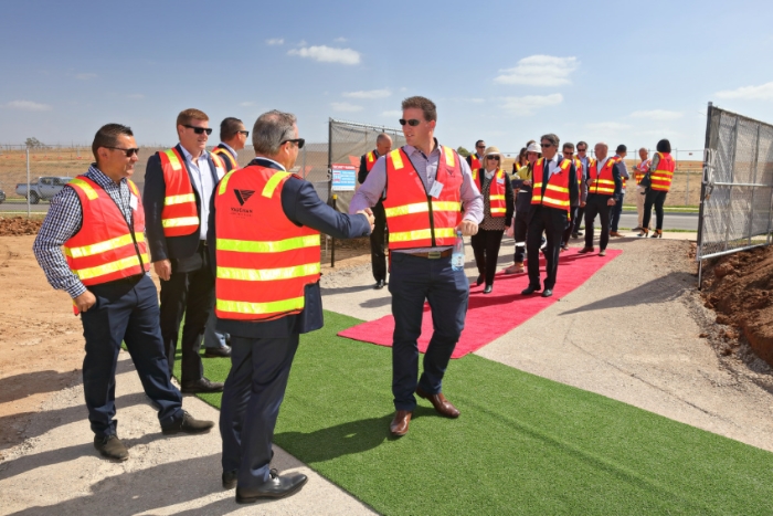 Commercial event photography of a SOD turn ceremony. Shows a group of business people arriving at an empty construction site.