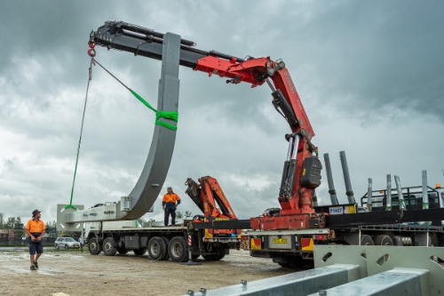 Industrial photography in Sydney of a crane lifting a large steel structure off a truck.