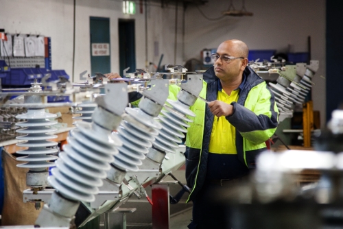 Infrastructure photography of a man working on high voltage insulators.