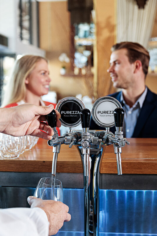 photo of water dispenser being used with customers in the background