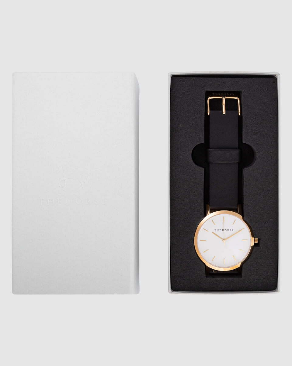 image of a gold watch with black strap in a case