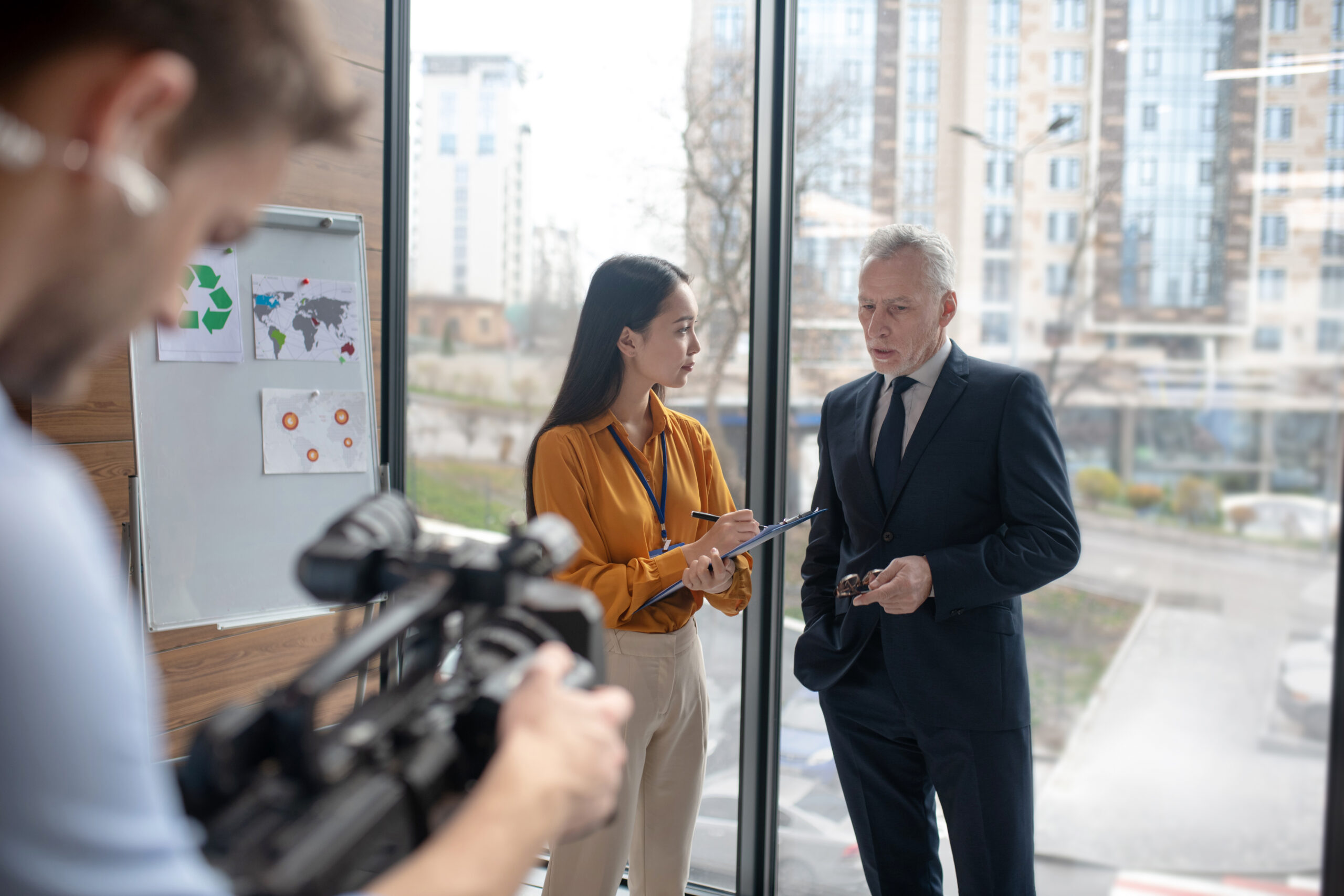 Behind the scenes of a corporate video filming in Sydney. Shows videographer, man and lady in an office building.