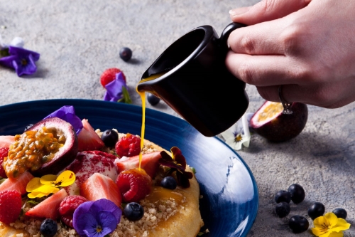 Styled food photography for menu - ricotta pancakes with syrup being poured.