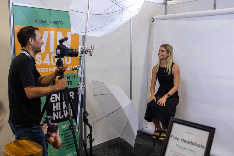 Professional photographer taking a corporate headshot of a lady on a white background in a photography studio.